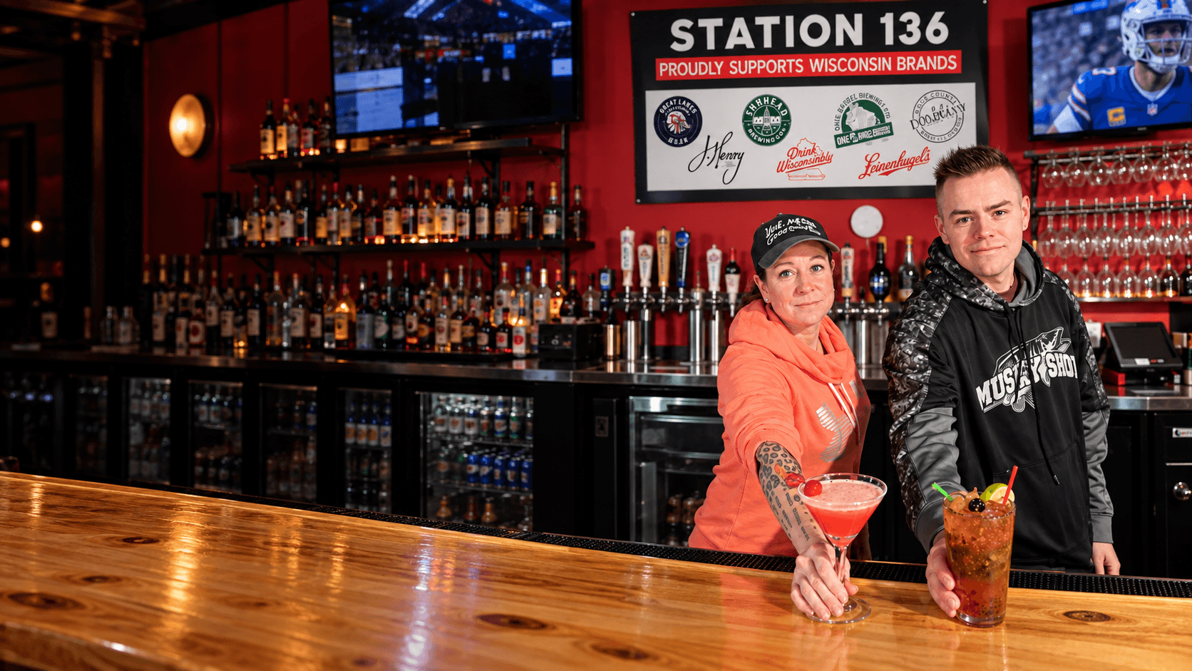 Two Station 136 staff members welcoming guests from behind the bar